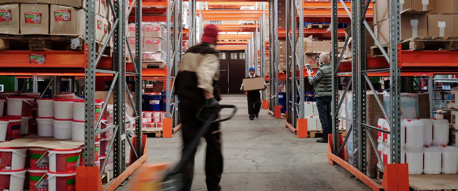 Warehouse worker moving parcels along a racking aisle